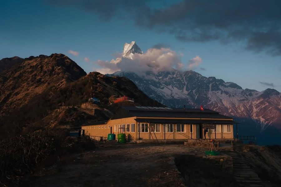 Teahouse lodge with Machhapuchhre’s snowy summit glowing at dusk.